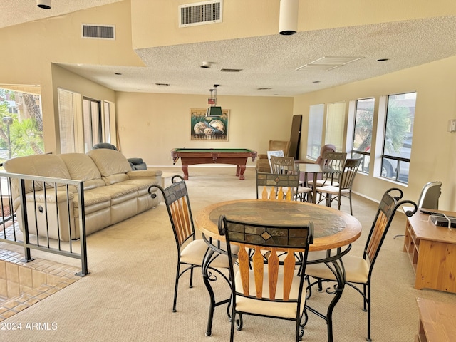 carpeted dining space with a wealth of natural light, pool table, and a textured ceiling