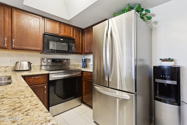 kitchen with appliances with stainless steel finishes, brown cabinetry, and a sink