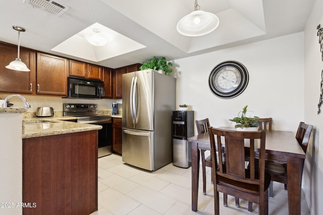 kitchen with a tray ceiling, stainless steel appliances, visible vents, a sink, and light stone countertops