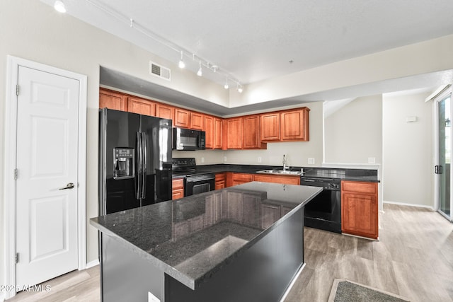 kitchen with light wood-style flooring, a sink, visible vents, black appliances, and brown cabinetry