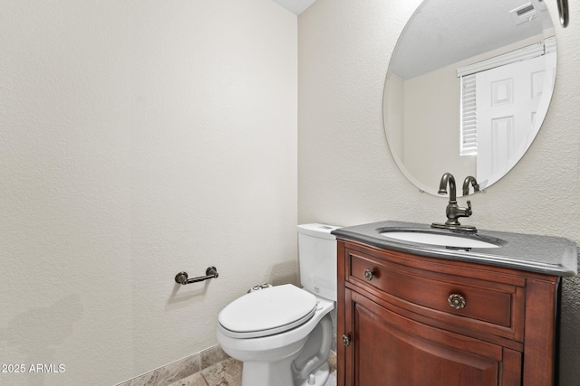 bathroom with toilet, a textured wall, visible vents, and vanity