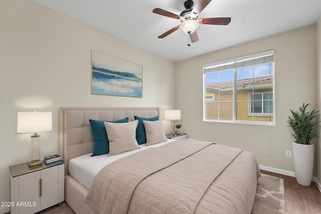 bedroom featuring ceiling fan, baseboards, and wood finished floors