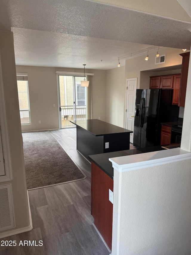 kitchen featuring a textured ceiling, wood finished floors, visible vents, black refrigerator with ice dispenser, and dark countertops