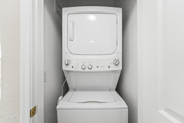 laundry room featuring a textured wall and stacked washing maching and dryer