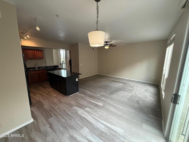 kitchen with a healthy amount of sunlight, dark countertops, a sink, and a center island