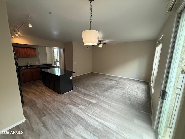 kitchen with baseboards, light wood-type flooring, a wealth of natural light, and a center island