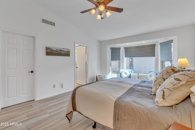 bedroom featuring ceiling fan, visible vents, baseboards, vaulted ceiling, and light wood-style floors