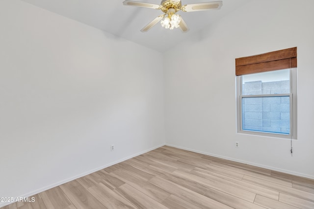 spare room featuring light wood-type flooring, ceiling fan, baseboards, and lofted ceiling