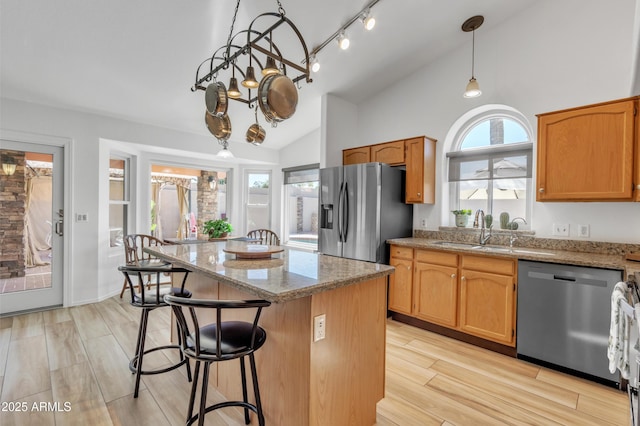 kitchen featuring lofted ceiling, a breakfast bar area, appliances with stainless steel finishes, a center island, and a sink