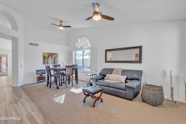 living room featuring lofted ceiling, visible vents, carpet flooring, ceiling fan, and baseboards