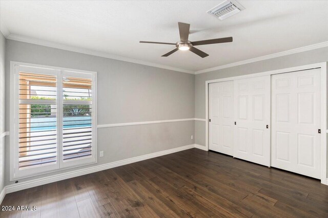 unfurnished bedroom with ornamental molding, dark hardwood / wood-style floors, ceiling fan, and a closet