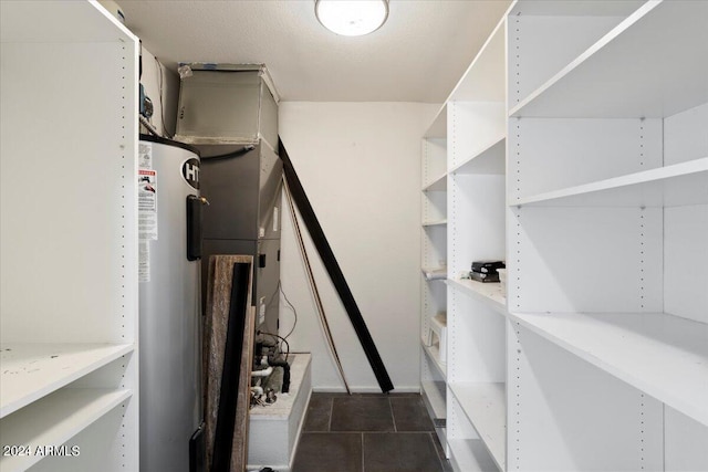 spacious closet with water heater and dark tile patterned floors