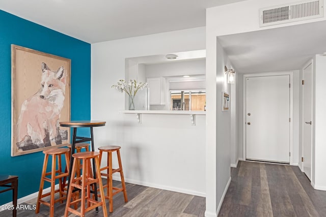 hall featuring wood finished floors, visible vents, and baseboards