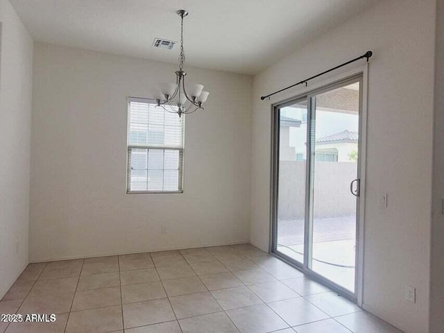 unfurnished room with an inviting chandelier, light tile patterned floors, and plenty of natural light