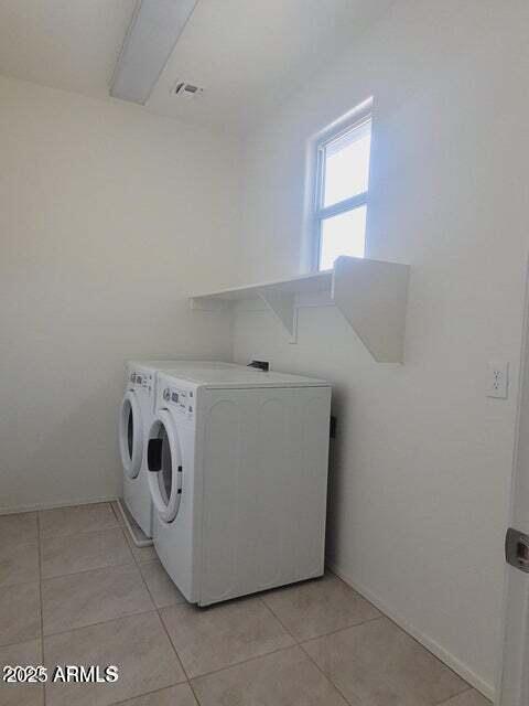 clothes washing area featuring washer and dryer and light tile patterned flooring