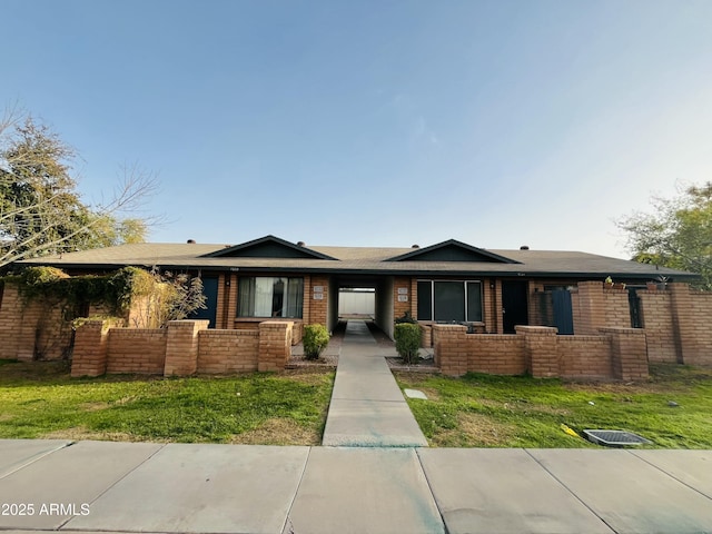 ranch-style house featuring a front yard, fence, and brick siding