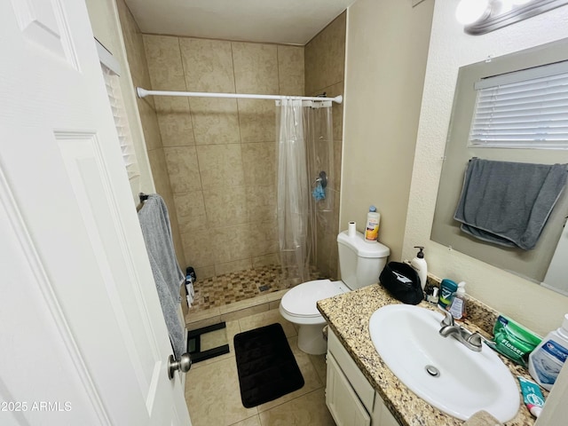 bathroom with a stall shower, vanity, toilet, and tile patterned floors