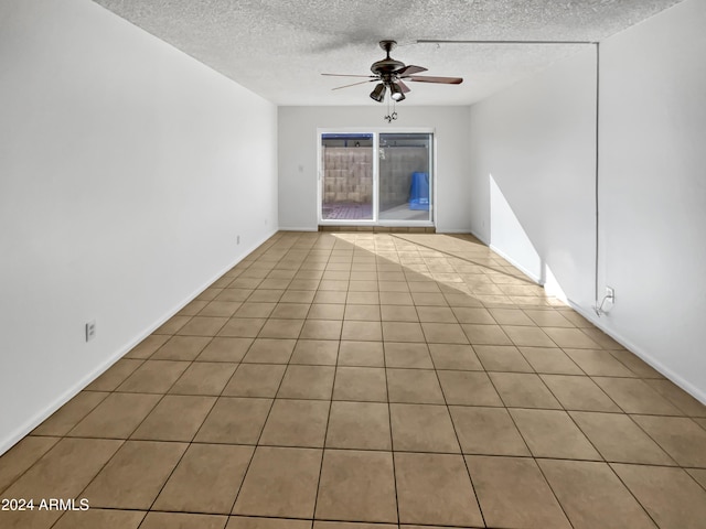 unfurnished room with ceiling fan, light tile patterned floors, and a textured ceiling