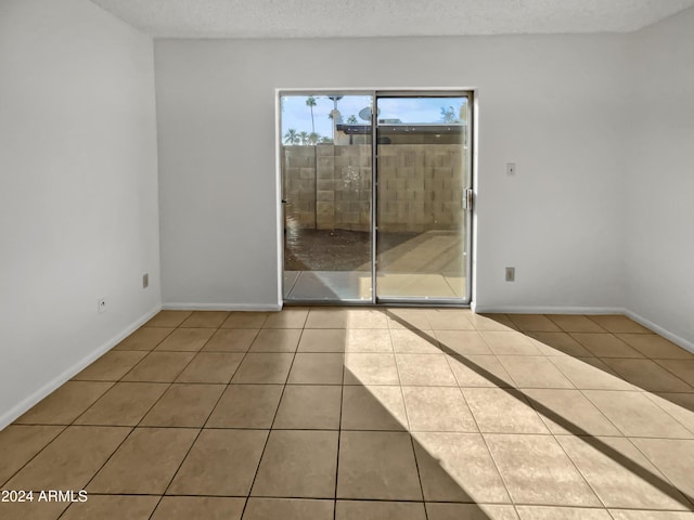 spare room featuring a textured ceiling and tile patterned floors