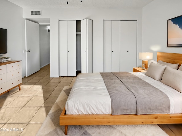 tiled bedroom featuring multiple closets