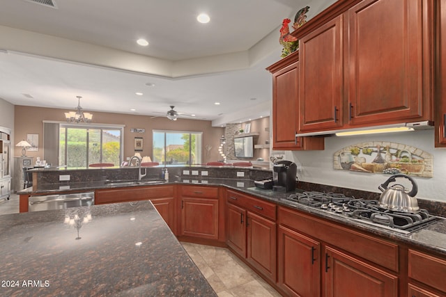 kitchen featuring ceiling fan with notable chandelier, dark stone countertops, sink, and stainless steel appliances