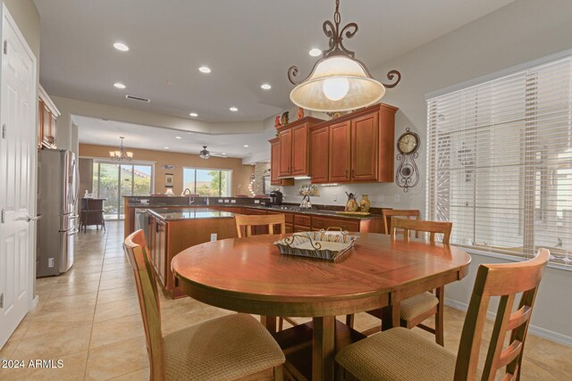 tiled dining area featuring ceiling fan with notable chandelier and sink