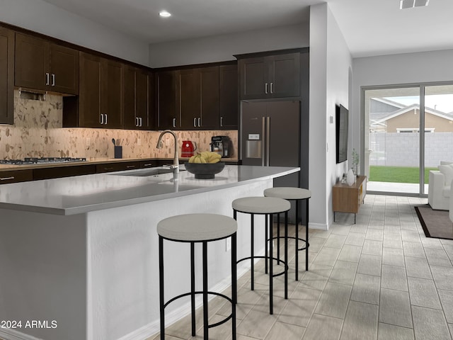 kitchen with a kitchen island with sink, stainless steel gas cooktop, light countertops, and a sink