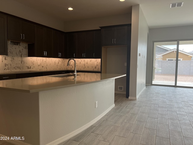 kitchen featuring a kitchen island with sink, light countertops, a sink, and visible vents