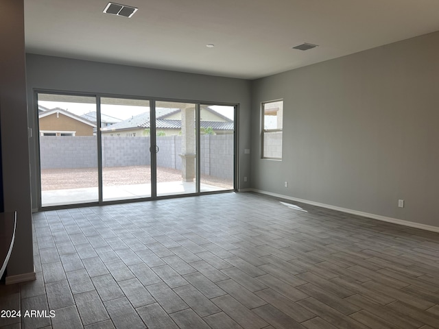 empty room with wood finished floors, visible vents, and baseboards