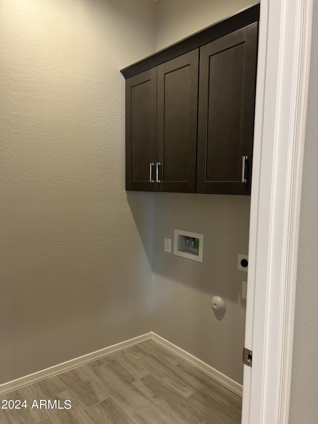 laundry area with hookup for a washing machine, cabinet space, hookup for an electric dryer, light wood-type flooring, and baseboards