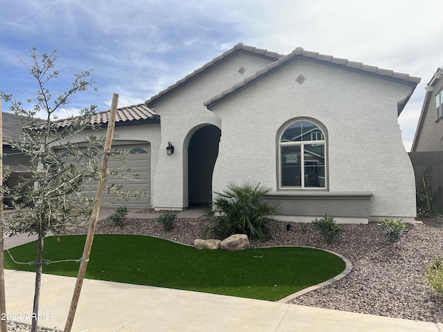 mediterranean / spanish home with a tiled roof, an attached garage, and stucco siding