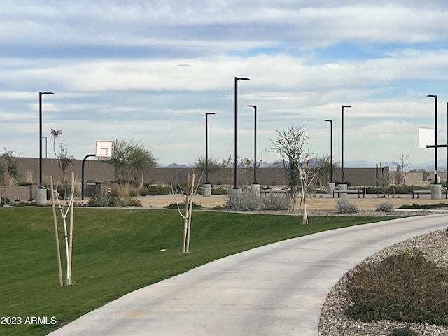 surrounding community with a mountain view, basketball court, and a lawn