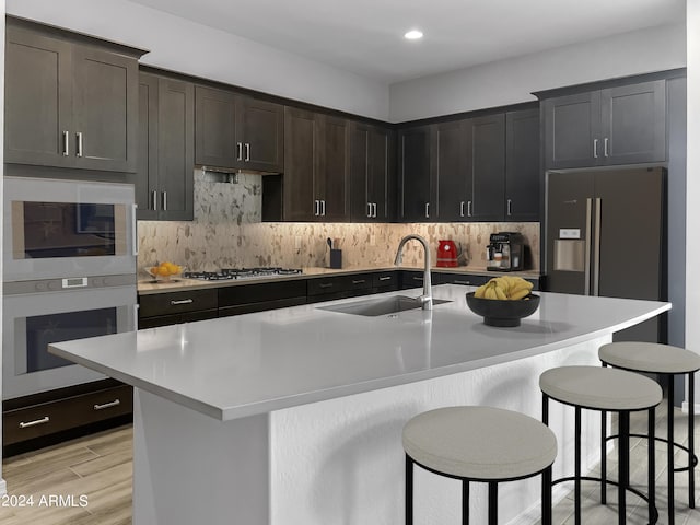 kitchen with stainless steel appliances, a kitchen island with sink, a breakfast bar area, and sink