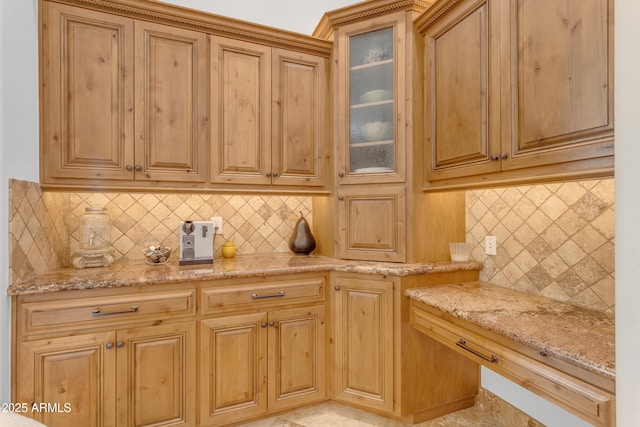 kitchen with tasteful backsplash, glass insert cabinets, and light stone countertops