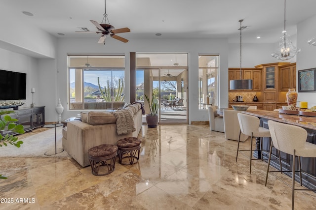 living room featuring ceiling fan, marble finish floor, a high ceiling, and baseboards