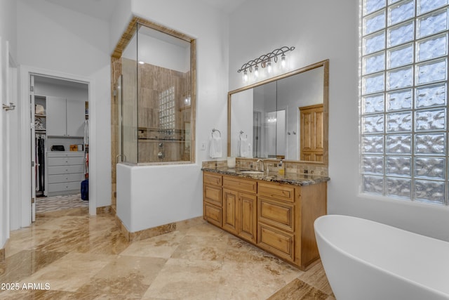 bathroom with a stall shower, a spacious closet, a freestanding bath, and vanity