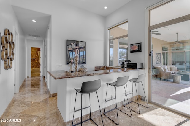 kitchen featuring visible vents, a peninsula, marble finish floor, a kitchen bar, and recessed lighting