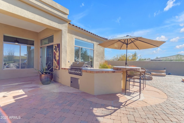 view of patio / terrace featuring exterior bar, fence, grilling area, and exterior kitchen