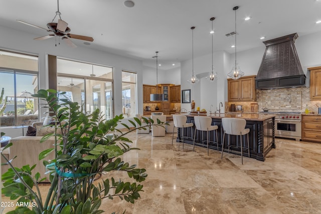 kitchen with light stone counters, a breakfast bar, high end range, custom exhaust hood, and backsplash