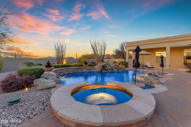 pool at dusk featuring a fenced backyard, an outdoor pool, a patio, and an in ground hot tub