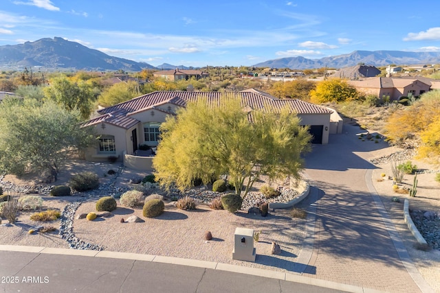 exterior space featuring a garage, decorative driveway, a mountain view, and stucco siding