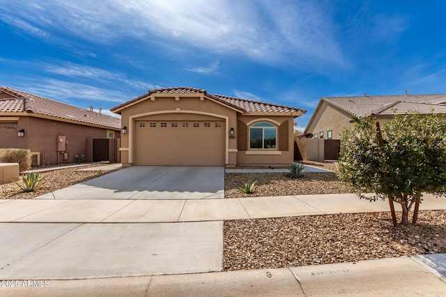 mediterranean / spanish-style house featuring a garage, driveway, a tiled roof, and stucco siding