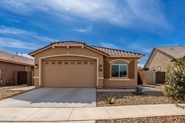 mediterranean / spanish home featuring driveway, an attached garage, a tile roof, and stucco siding