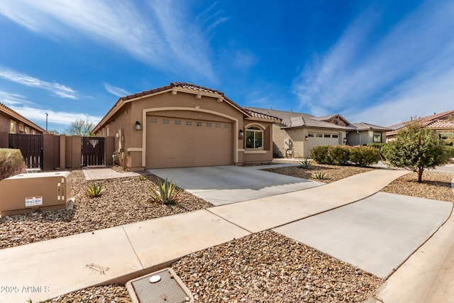 mediterranean / spanish house featuring a garage, concrete driveway, a tiled roof, fence, and stucco siding