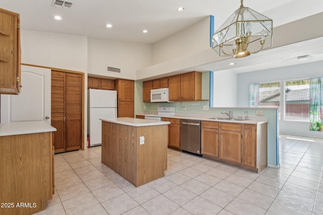 kitchen featuring a kitchen island, sink, hanging light fixtures, a notable chandelier, and white appliances