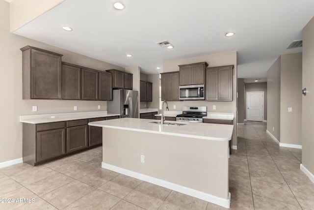 kitchen with dark brown cabinets, sink, appliances with stainless steel finishes, and an island with sink