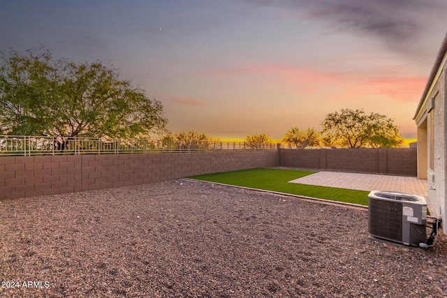 yard at dusk with a patio area and central air condition unit