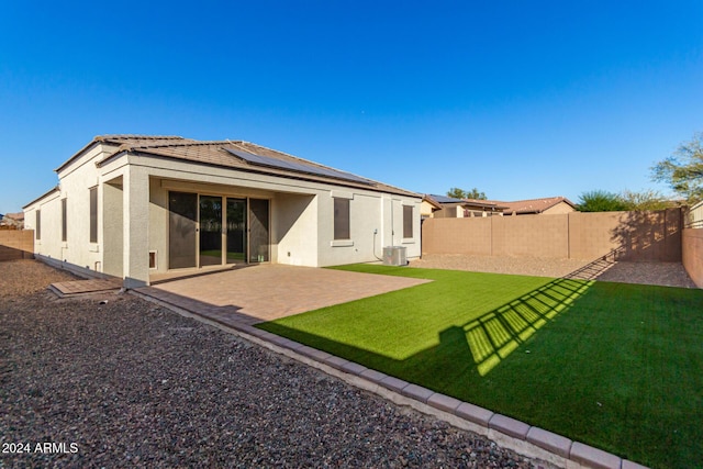 back of house with a lawn, solar panels, cooling unit, and a patio area