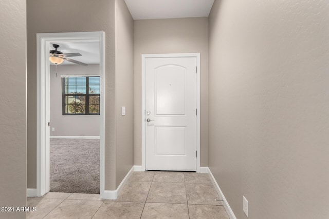 doorway featuring ceiling fan and light tile patterned floors