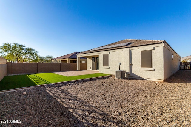 back of property with a patio area, a yard, and central AC